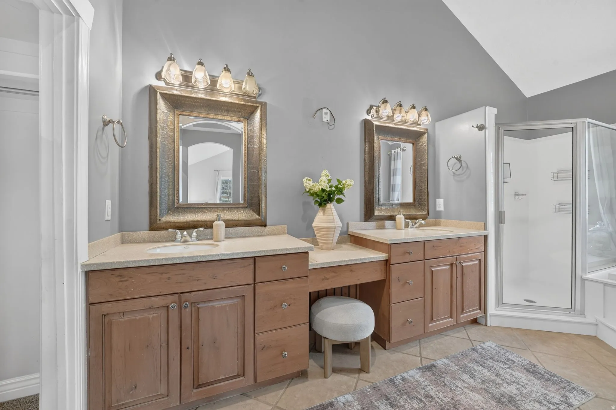 Dual vanity with light wood-finish cabinetry, integrated sinks, and individual mirrors