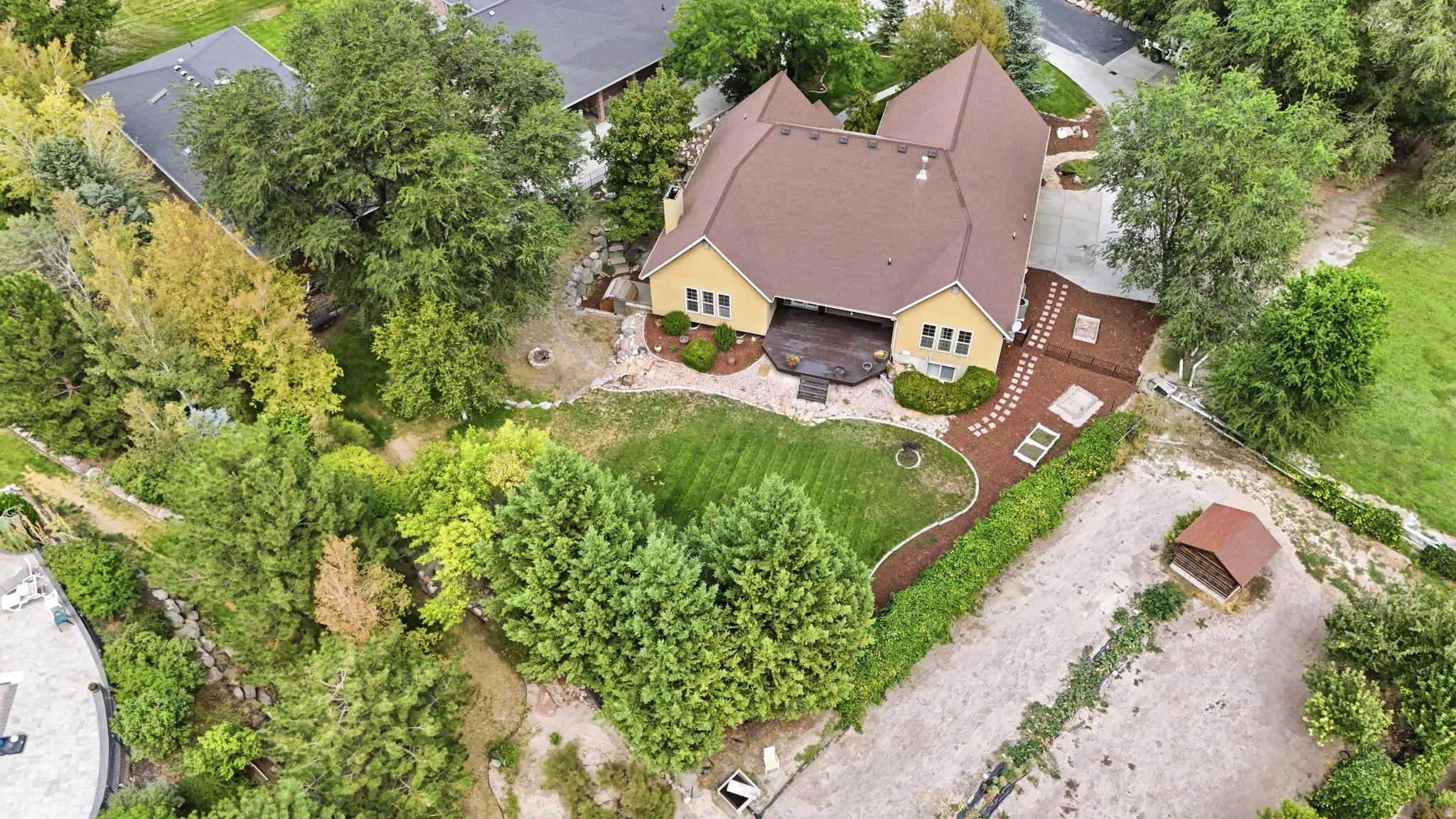 Spacious property featuring a large backyard, concrete driveway, and mature trees