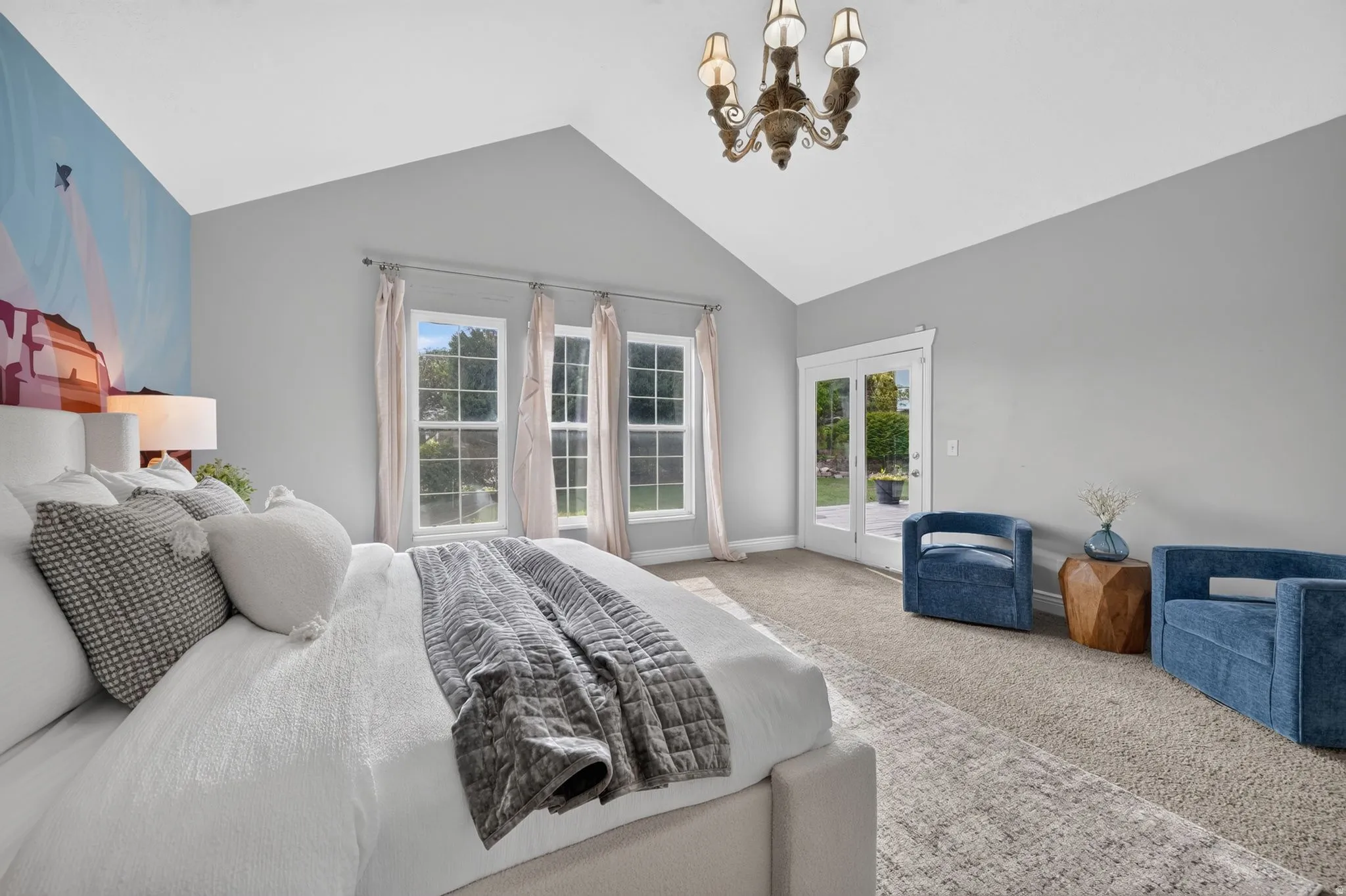 Vaulted ceiling with an ornate chandelier, multiple windows with natural light, and French doors leading to exterior