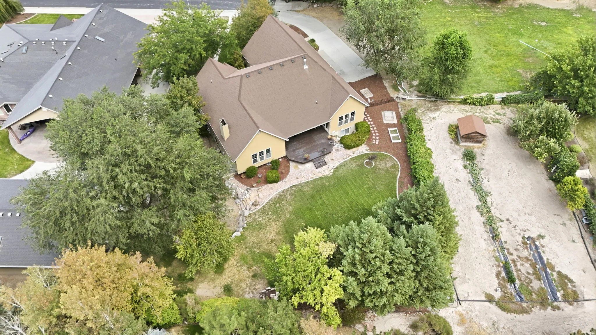 Expansive property featuring a detached shed, established trees, and a spacious rear deck