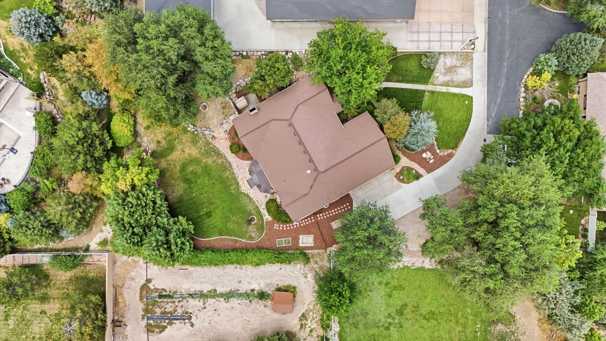 Expansive property featuring mature trees, a manicured lawn, and paved driveway