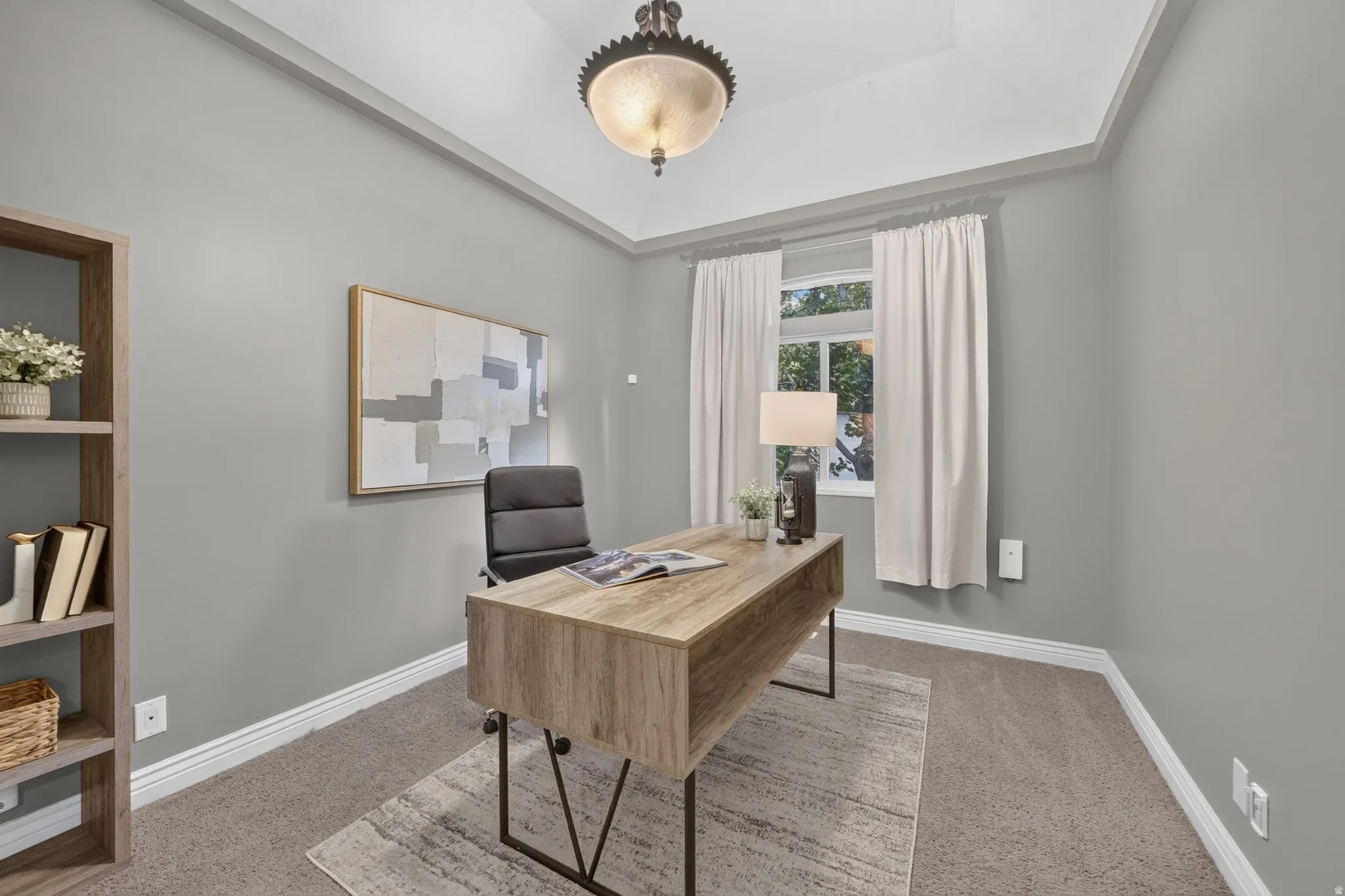 Tray ceiling with a decorative semi-flush mount fixture, neutral wall color, and window with natural light