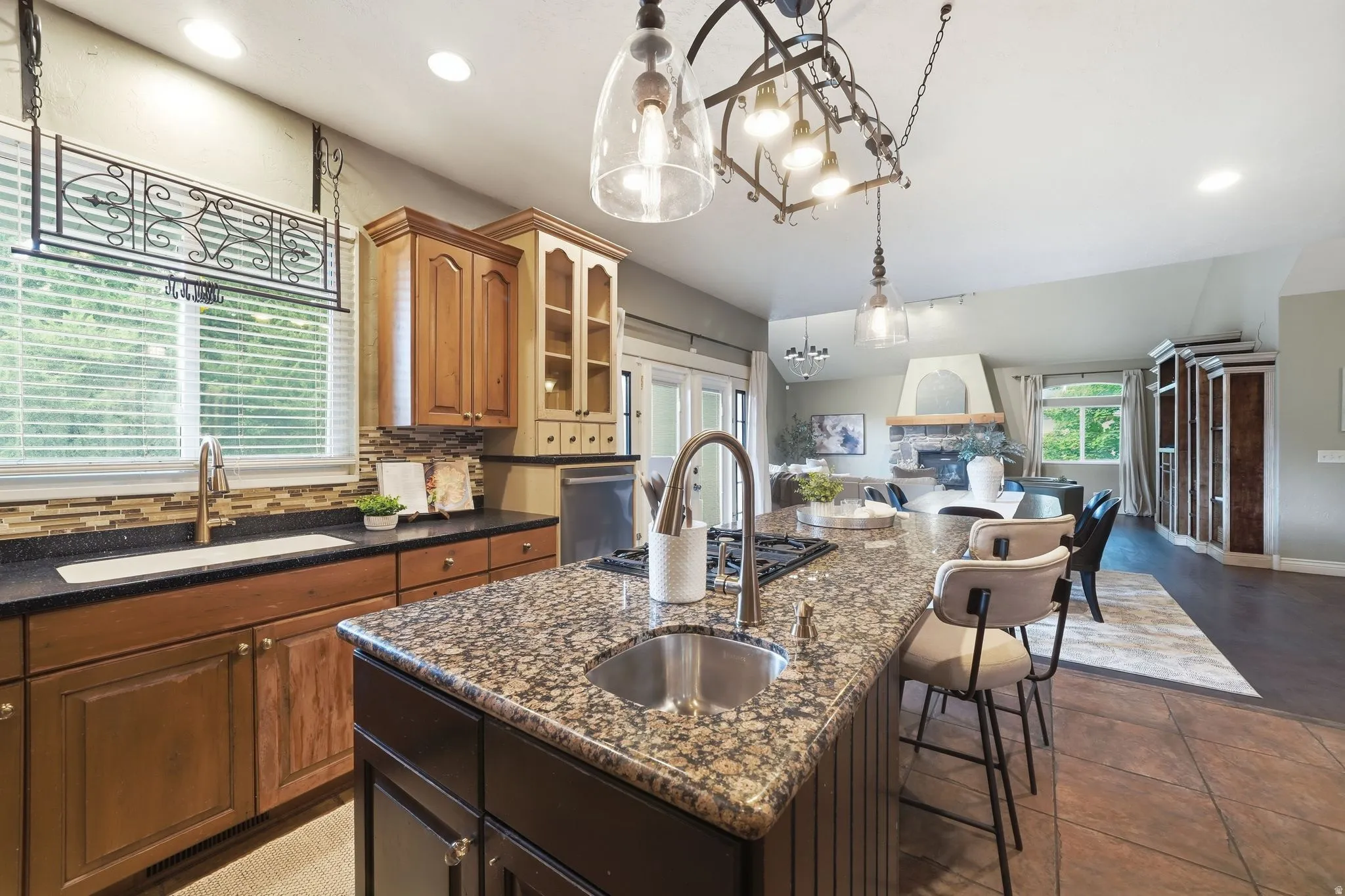 Gourmet kitchen featuring a large central island with seating, granite countertops, and a stainless steel sink with a gooseneck faucet