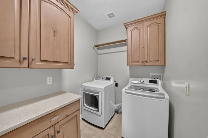 Laundry area featuring upper and lower cabinetry, a built-in countertop, and a storage shelf