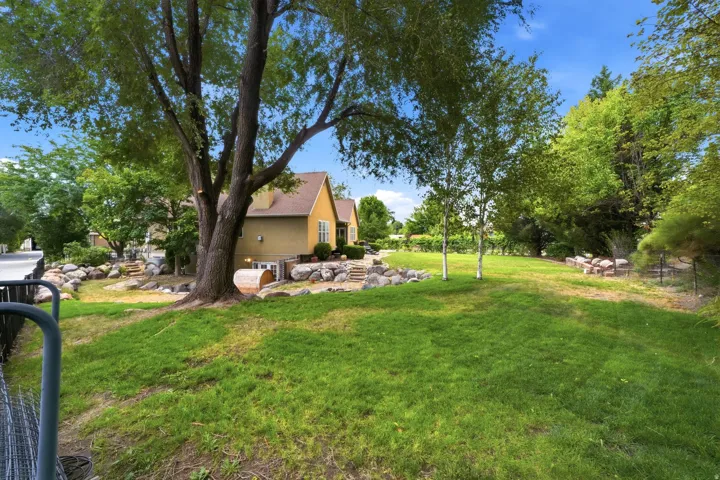 Expansive green lawn with mature trees and natural rock landscaping