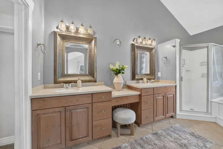 Dual vanity with light wood-finish cabinetry, integrated sinks, and individual mirrors