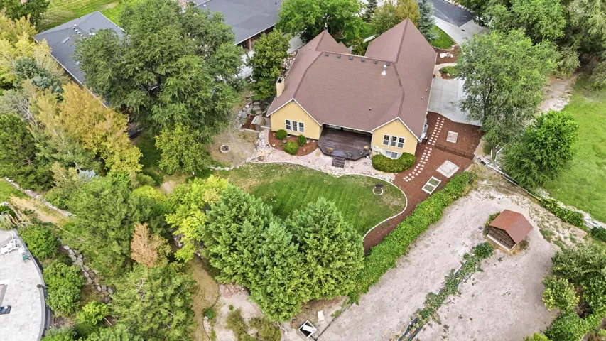 Spacious property featuring a large backyard, concrete driveway, and mature trees