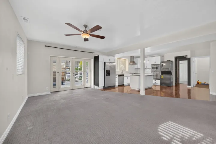 Open-concept living space featuring a ceiling fan, french doors, and carpet flooring