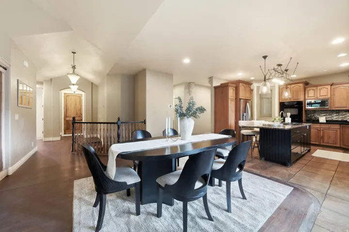 Vaulted ceilings, wood-finish flooring, staircase with wood railing, kitchen island with seating, and wood cabinetry