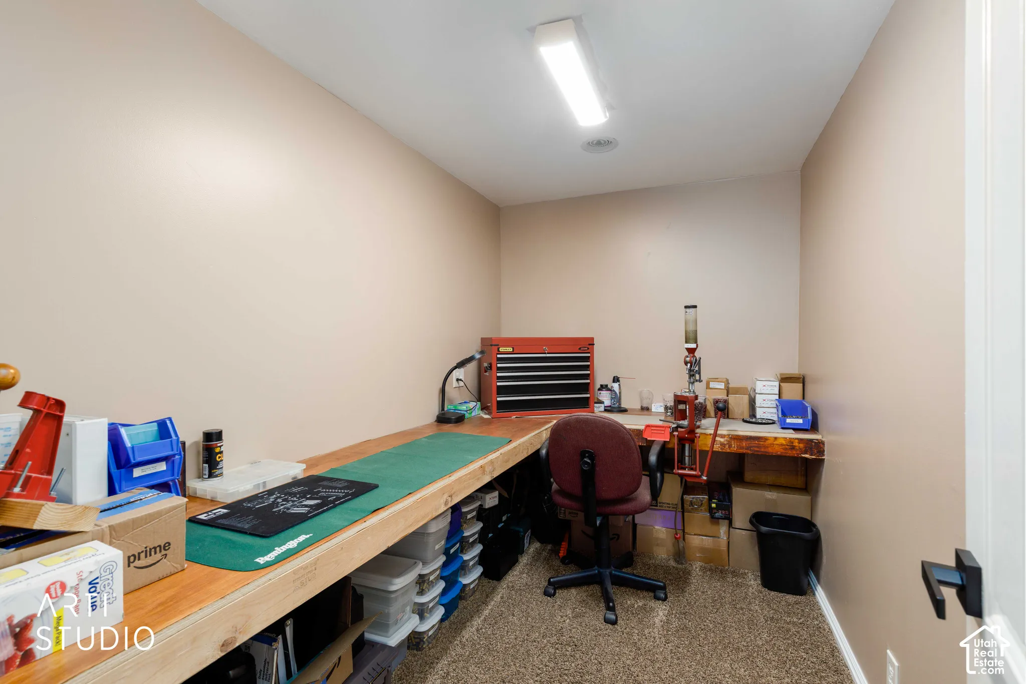 Large hall closet with ceiling light, a built-in L-shaped workbench, and brown carpeted flooring.