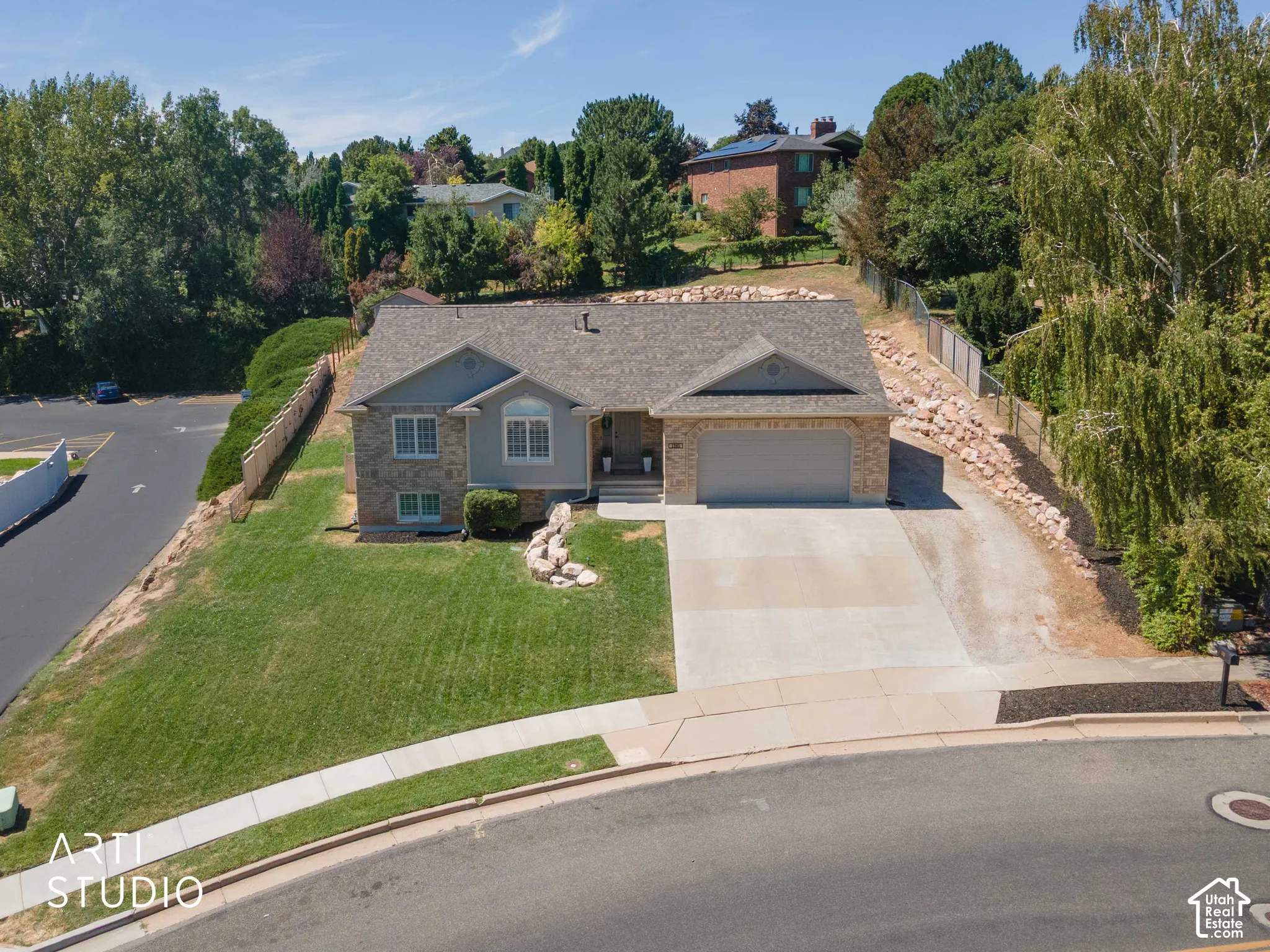 Brick and stucco exterior with an attached two-car garage, concrete driveway, side parking area and front lawn