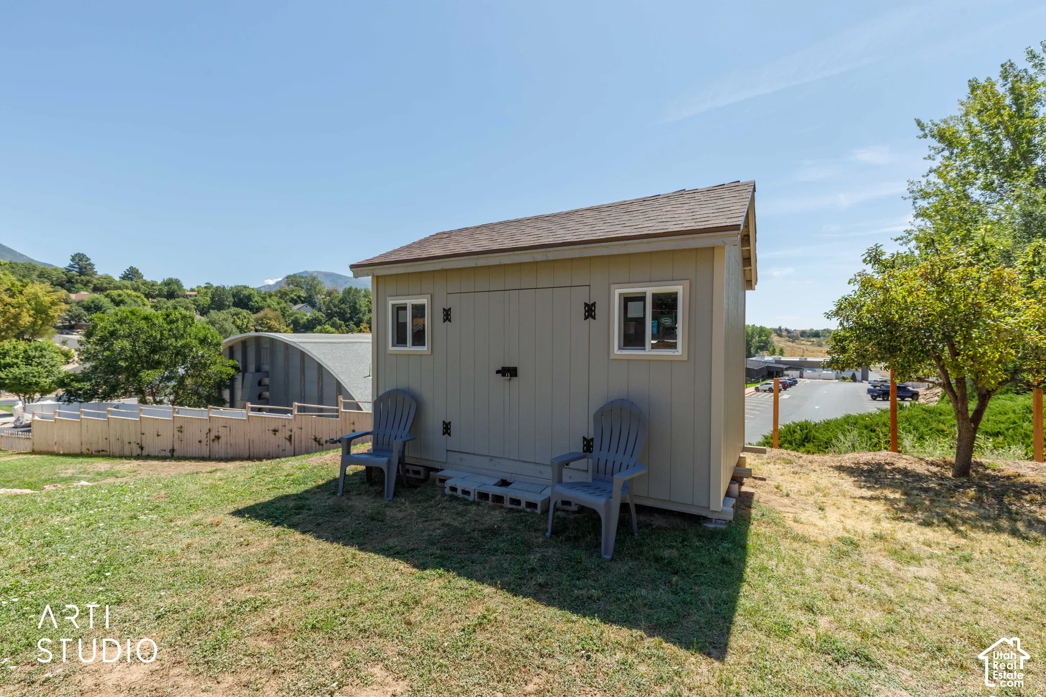 Newer storage shed with four windows, double doors and a shingle roof