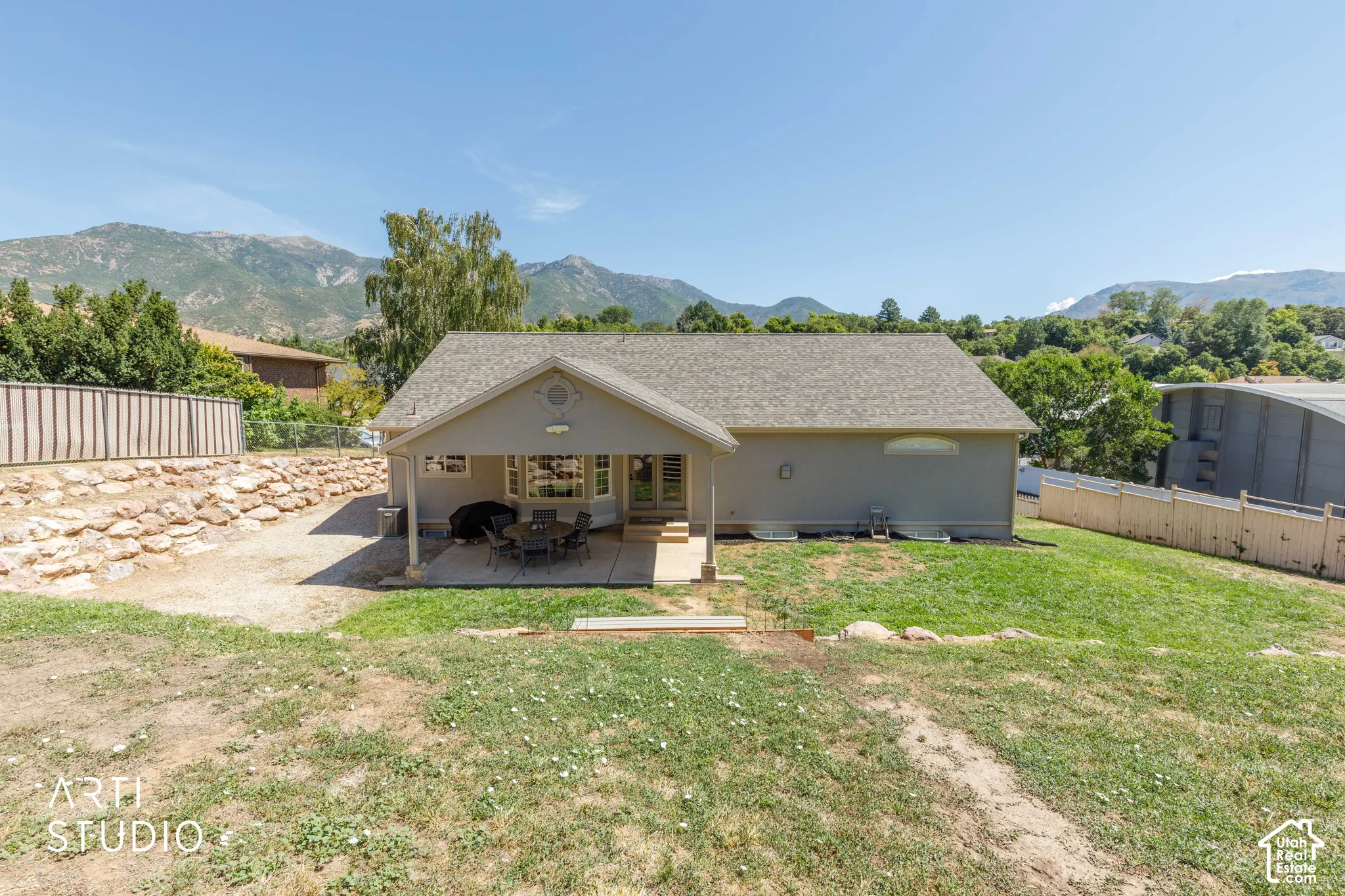 Rear exterior featuring a covered patio, extensive grass area, bay window, and a partial perimeter fence