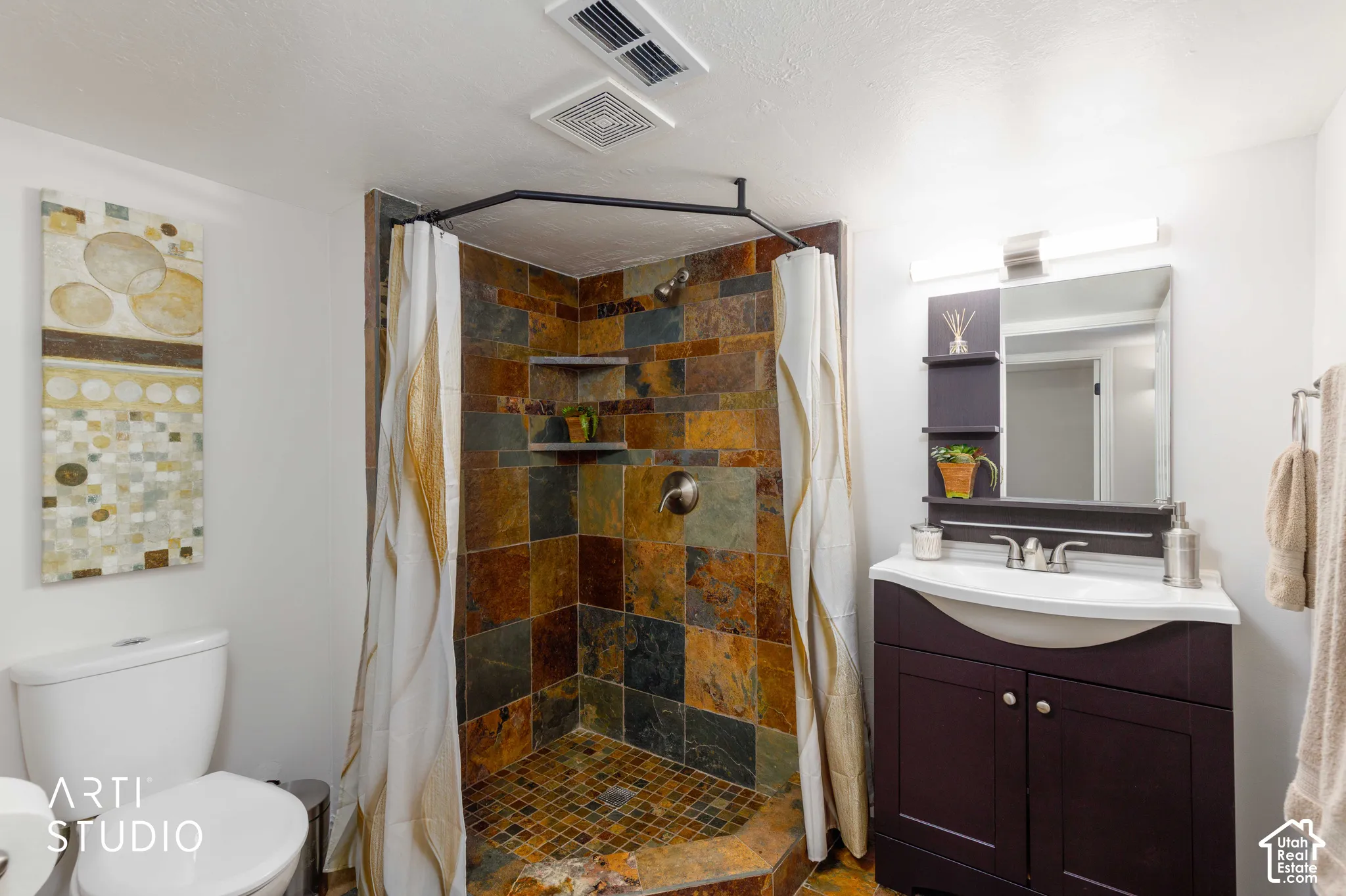 3/4 Bath with Shower designed with slate stone tile surround and floor, vanity and mirror, and a custom designed curved shower rod.