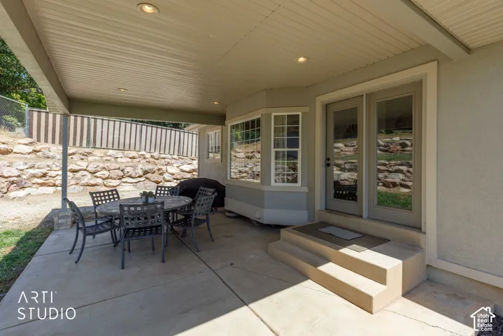 Covered concrete patio with recessed lighting and box bay window and stairs leading from interior family room.