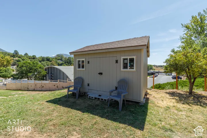 Newer storage shed with four windows, double doors and a shingle roof