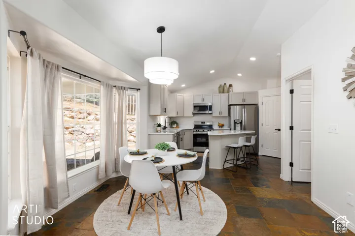Open Dining area featuring bay window and entry into Kitchen with updated stainless steel appliances, light Buff cabinetry, and an eat-at island