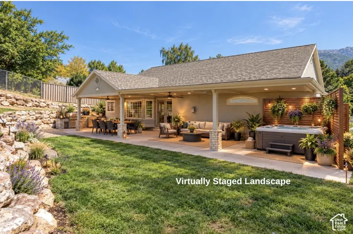 Extended & Covered concrete patio with recessed lighting and stone-accented columns, built-in hot tub, and tiered rock landscaping - Virtural landscape- Not Existing