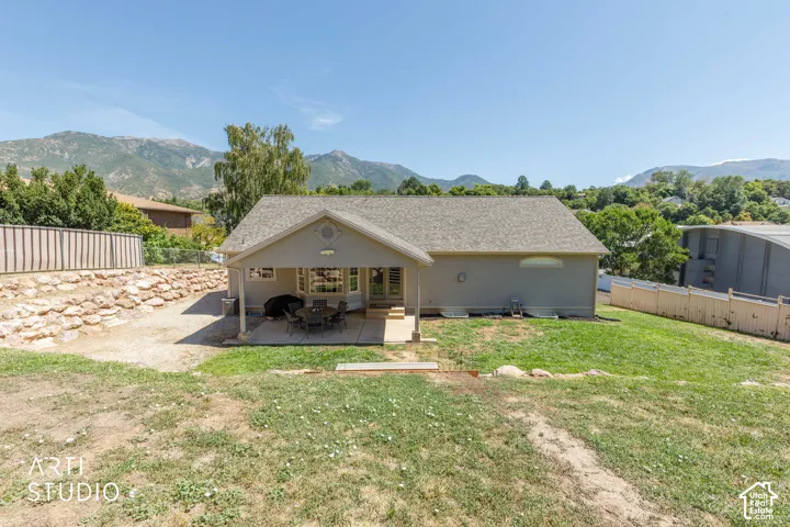 Rear exterior featuring a covered patio, extensive grass area, bay window, and a partial perimeter fence