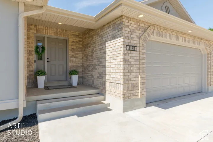 Brick exterior with arched garage door surround, concrete driveway, concrete porch, and multiple recessed soffit lights
