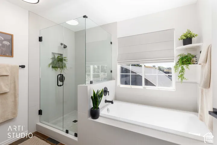 Euro style glass-enclosed tiled shower with matte black fixtures, built-in recessed shelf, and tiled surround soaking tub