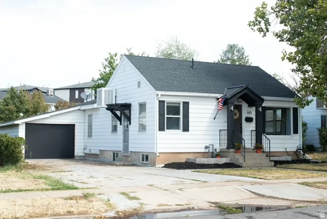 White exterior siding with black shutters and trims, covered front entry with black metal railing, side basement apartment entrance, attached garage and shingle roof