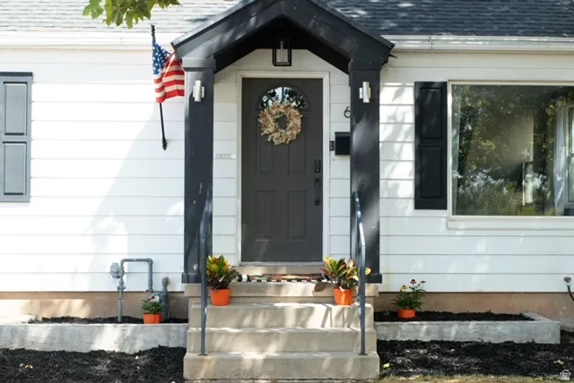 White horizontal siding exterior with black shutters and porch trim, with post accent lighting.