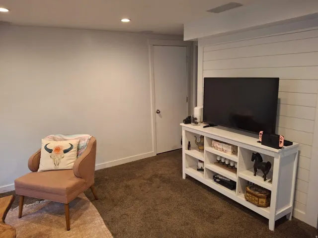 Recessed ceiling lighting, white painted walls, shiplap accent wall, white built-in shelving, and carpet flooring