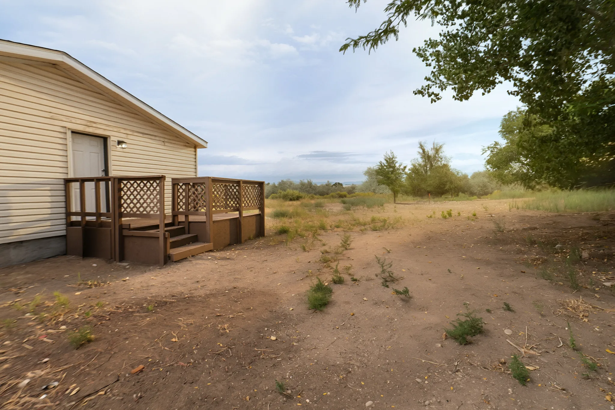 Exterior featuring horizontal siding, a private deck with lattice railing, and a functional outdoor light fixture