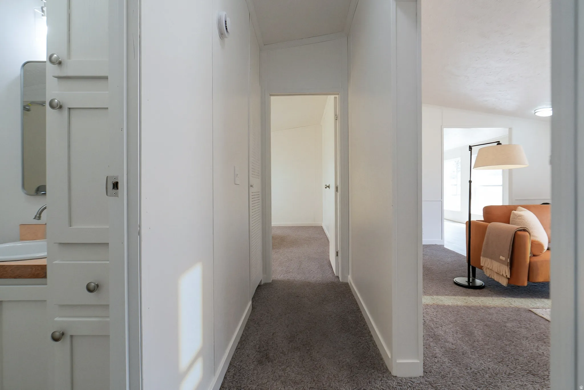 Hallway with carpet flooring, white walls, and built-in vanity with wood-finish countertop