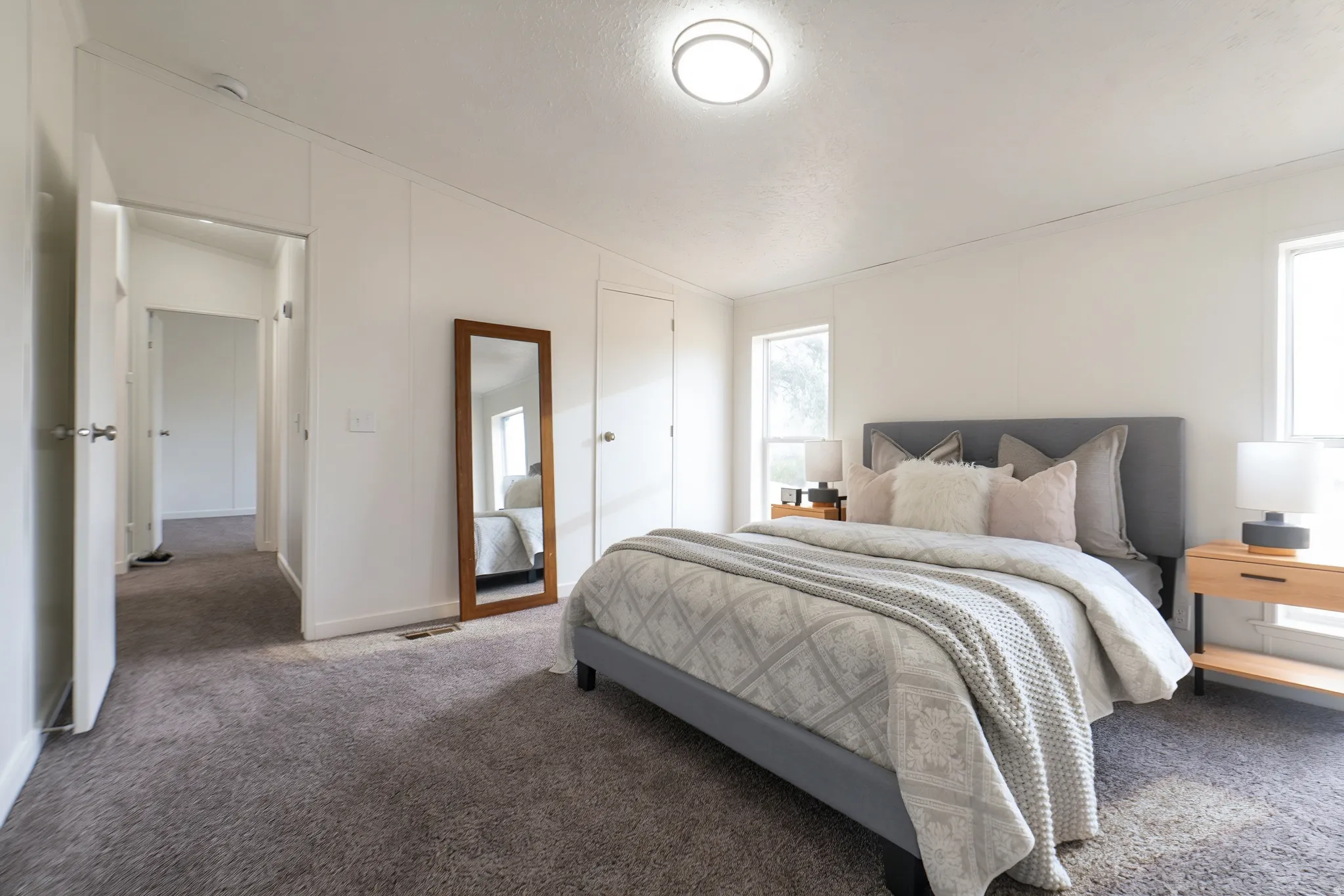 Carpeted room with white walls, two windows, and a flush-mount ceiling light fixture
