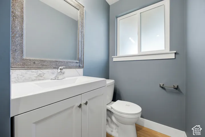 White vanity with a single basin, chrome faucet, and a patterned mirror