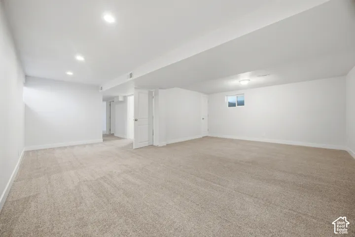Spacious room with new carpet, white walls, recessed lighting, and an egress window