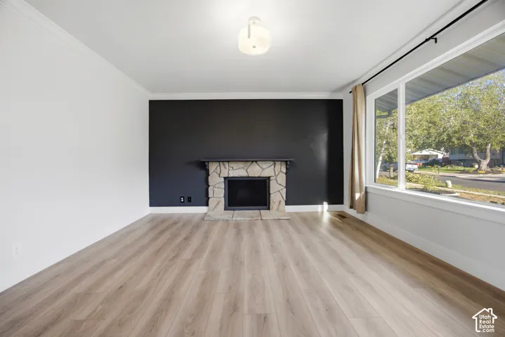 Stone fireplace with a dark accent wall, wood-finish flooring, and large picture windows