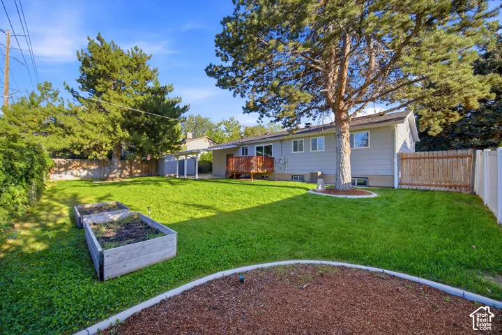Expansive backyard featuring a manicured lawn, raised garden beds, and mature trees