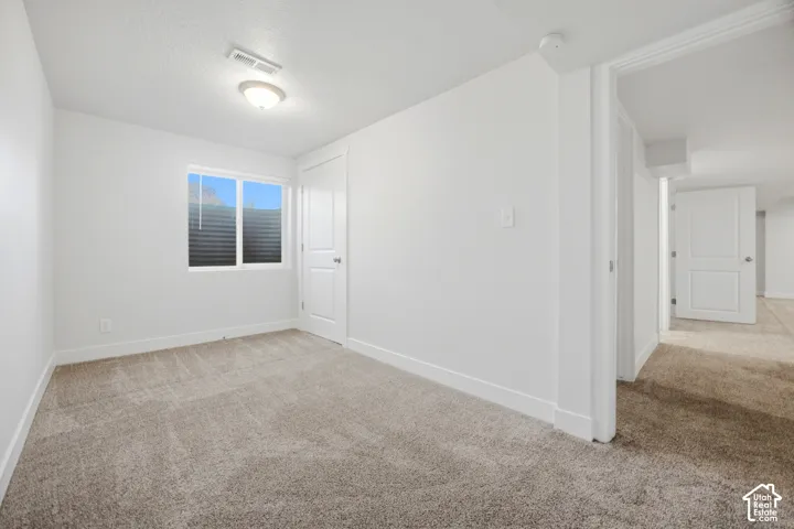 Neutral-toned carpeting, white painted walls, and a single window with blinds