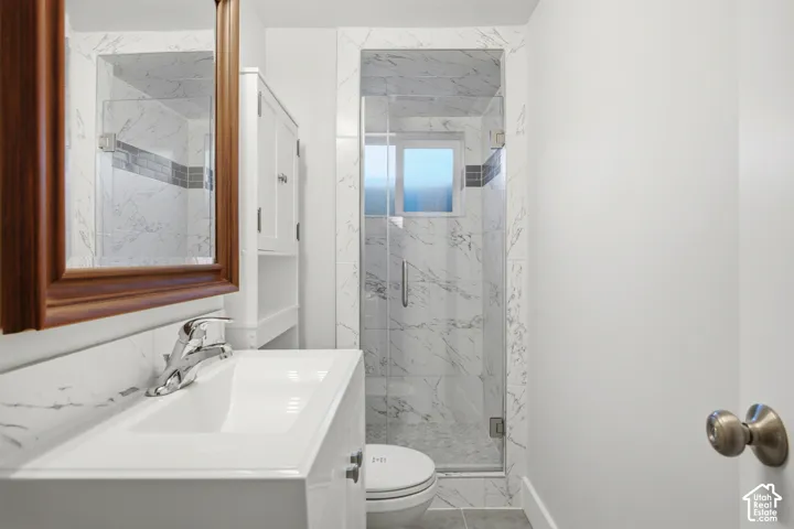 Modern bathroom with a glass-enclosed shower, tile surround, and a vanity with an integrated sink