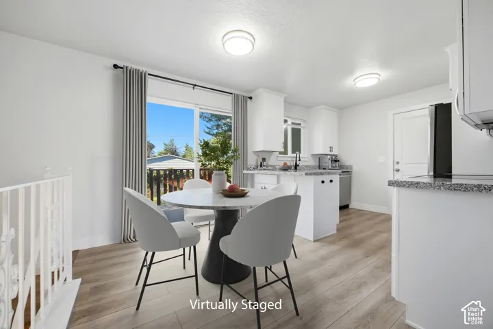 Light wood-finish flooring, white cabinetry, granite countertops, stainless steel appliances, and a sliding glass door