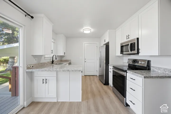 Kitchen featuring white cabinetry, granite-style countertops, stainless steel appliances, wood-finish flooring, and a sliding glass door
