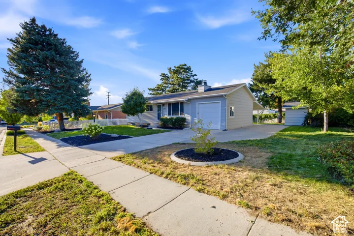 Single-story residence featuring light-colored siding, an attached garage, and a concrete driveway