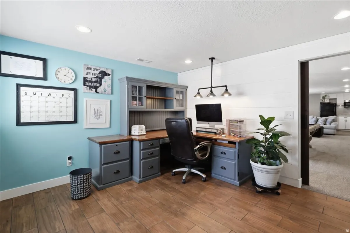 Wood-finish flooring, recessed lighting, and a built-in desk with overhead shelving