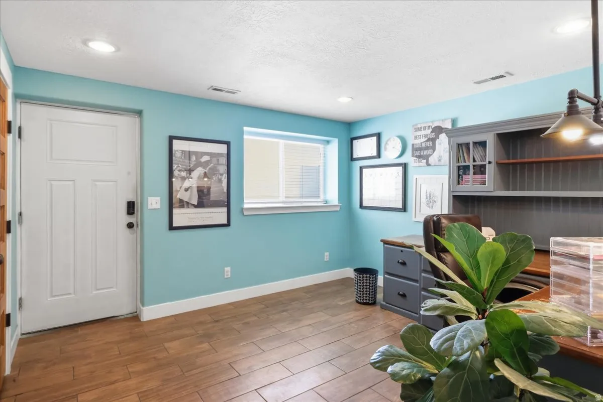 Recessed lighting, wood-finish flooring, white window blinds, and built-in shelving