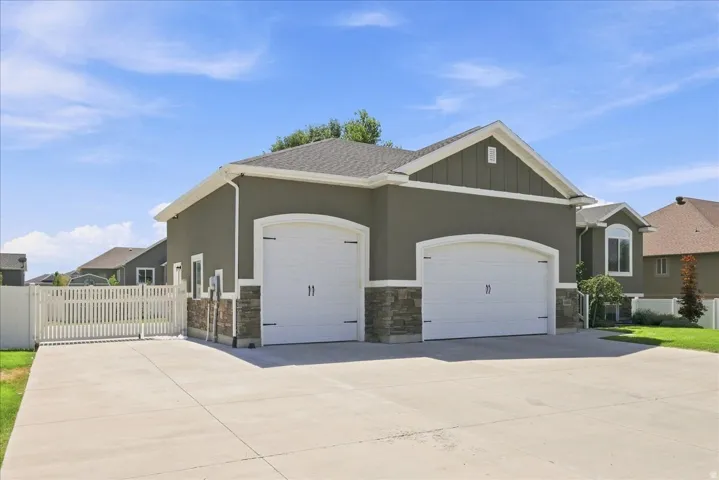 Three-car garage with arched doors, stone veneer accents, and an expansive concrete driveway