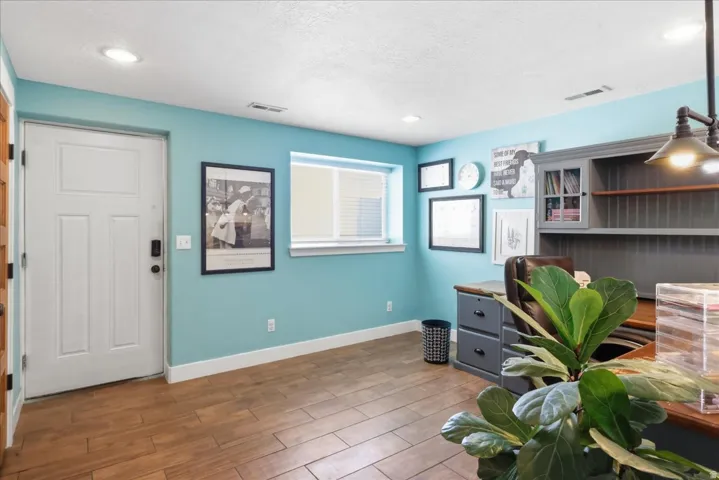 Recessed lighting, wood-finish flooring, white window blinds, and built-in shelving