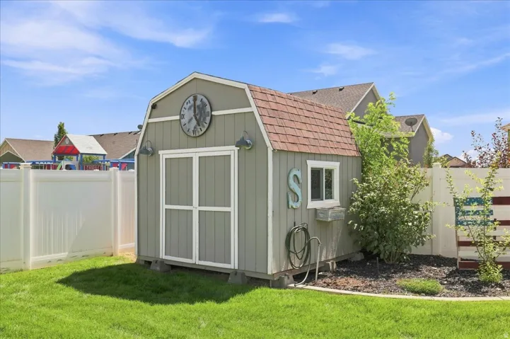 Storage shed with a gambrel roof, double doors, and a side window