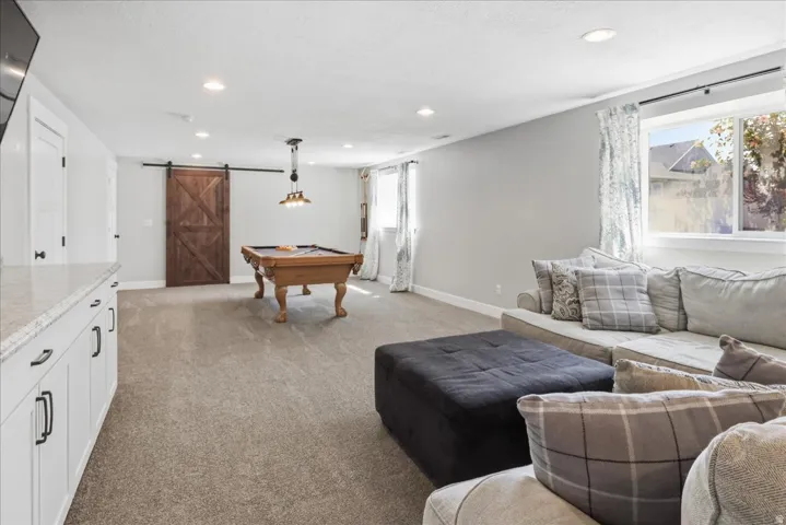 Recessed ceiling lighting, wood-finish barn door, window with natural light, built-in cabinetry, and a light-toned carpet