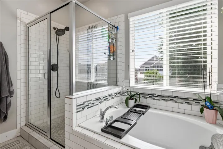Walk-in shower with clear glass enclosure and subway tile surround. Large garden tub.
