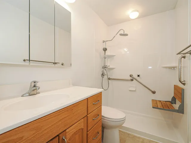 White vanity countertop with integrated sink, wood-finish cabinetry, and chrome fixtures