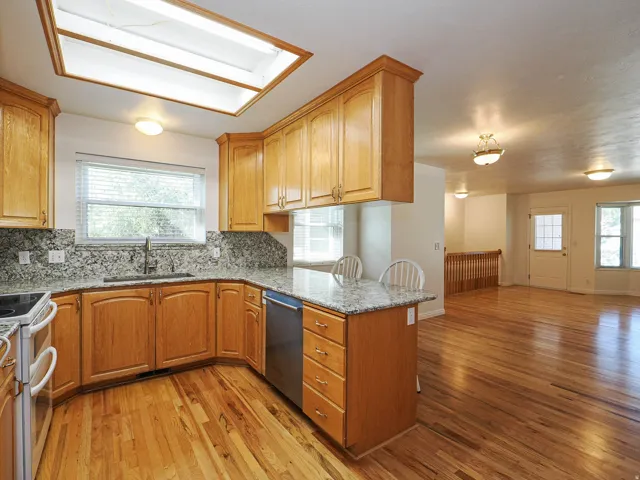 Kitchen featuring wood cabinetry, a stainless steel dishwasher, a single basin sink with a high-arc faucet, and granite countertops