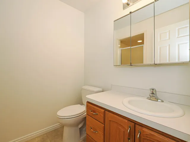 Vanity with wood-finish cabinetry, white countertop, and integrated oval sink